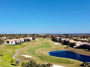 A golf course with a pond, surrounded by residential buildings.