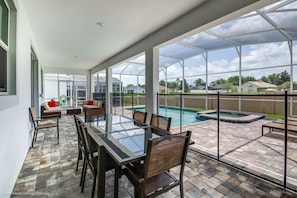 A covered patio with a glass table and chairs, a pool, and a view of the neighborhood. - Waterpark! Princess Room! 9 mi 2 Disney! 1672 (Davenport)