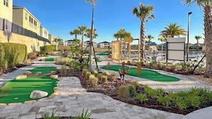 Een golfbaan met een pad van bakstenen, palmbomen en een helderblauwe lucht.