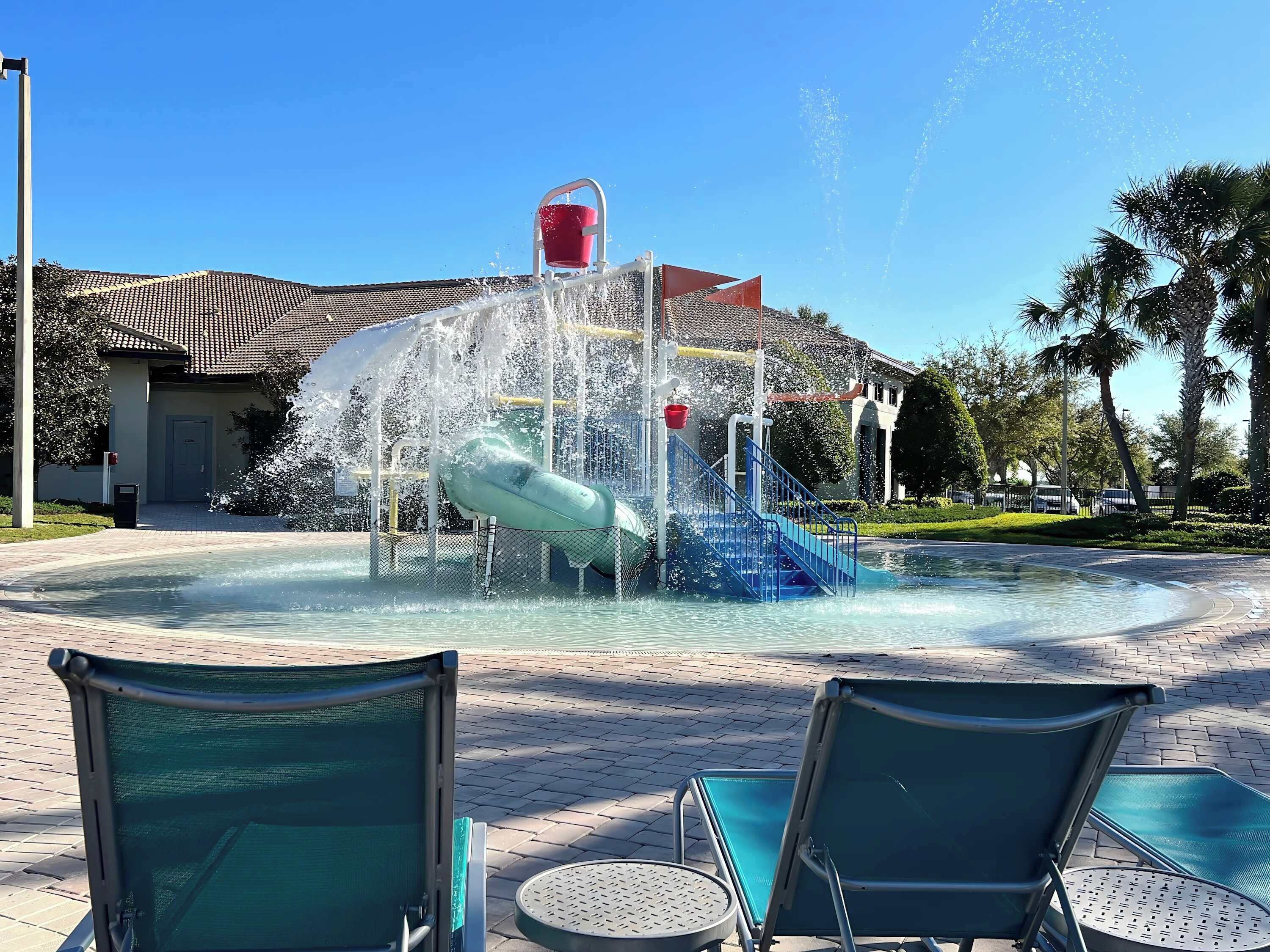 Un parc aquatique avec un toboggan, une piscine et des chaises longues.
