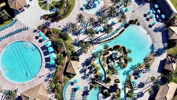 An aerial view of a resort with multiple swimming pools, sun loungers, and palm trees. - Private Pool & Spa | Game Room | Near Disney 8908 (Davenport)