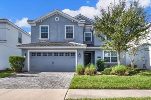 A two-story house with a grey facade, a tiled roof, and a front garage.