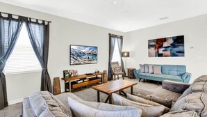 A living room with a sofa set, a coffee table, a TV, and artwork on the walls. - Private Pool & Spa | Game Room | Near Disney 8908 (Davenport)