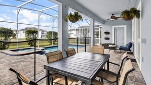 A covered patio with a pool, outdoor seating, and hanging planters. - Private Pool & Spa | Game Room | Near Disney 8908 (Davenport)