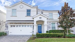 A two-story house with a blue front door, a garage, and a well-maintained lawn. - 101 Dalmatians | Theater | South Pool | Disney 8942 (Davenport)