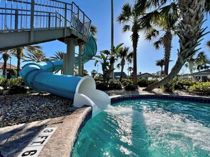 A water slide leading into a pool surrounded by palm trees and a clear blue sky. - Mickey! Ping Pong! Resort 9 Mi 2 Disney! 9022 (Davenport)