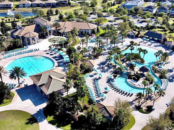 Un resort con una amplia piscina central, varias piscinas más pequeñas y un paisaje bien cuidado con palmeras y zonas de descanso.