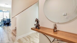 Un intérieur moderne avec une console en bois, un miroir rond et un petit objet décoratif.