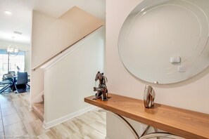 A modern interior with a wooden console table, a round mirror, and a small decorative item.