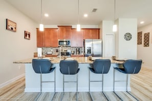 Una cocina moderna con armarios de madera, electrodomésticos de acero inoxidable y una isla central con taburetes.