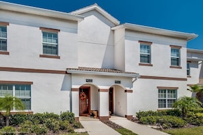 A two-story building with a white exterior and brown trim. It has two visible doors, numbered 9025 and 9023, and a small porch area.
