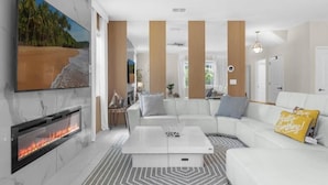 A modern living room with a fireplace, a white sofa, and a coffee table. - Harry Potter | Star Wars | Pool & Spa | Disney 9026 (Davenport)