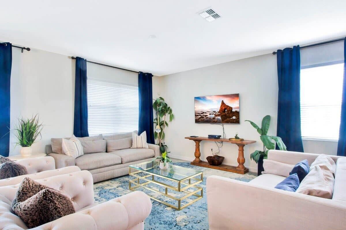 Ein Wohnzimmer mit einem beigen Sofa, einem Glastisch und einem großen Gemälde an der Wand.
