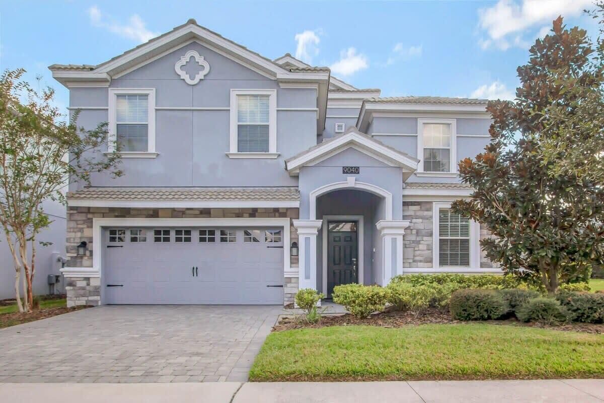 A two-story house with a garage, a stone facade, and a well-maintained lawn.