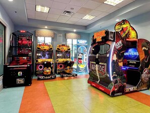 A gaming arcade with various machines, including a dinosaur-themed game and a Mickey Mouse-themed game.