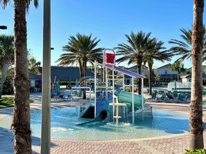A water park with a slide, a pool, and lounge chairs.