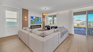 Una sala de estar moderna con un sofá modular, un televisor de pantalla plana y un amplio ventanal con vistas al exterior.