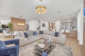 A modern living room with a sectional sofa, a coffee table, and a chandelier.