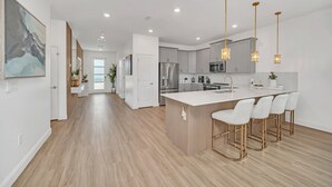 Una cocina moderna con una isla central, electrodomésticos de acero inoxidable e iluminación colgante.