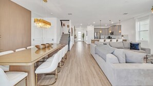 Un espacio habitable moderno con comedor, cocina y una escalera que sube a otro nivel.