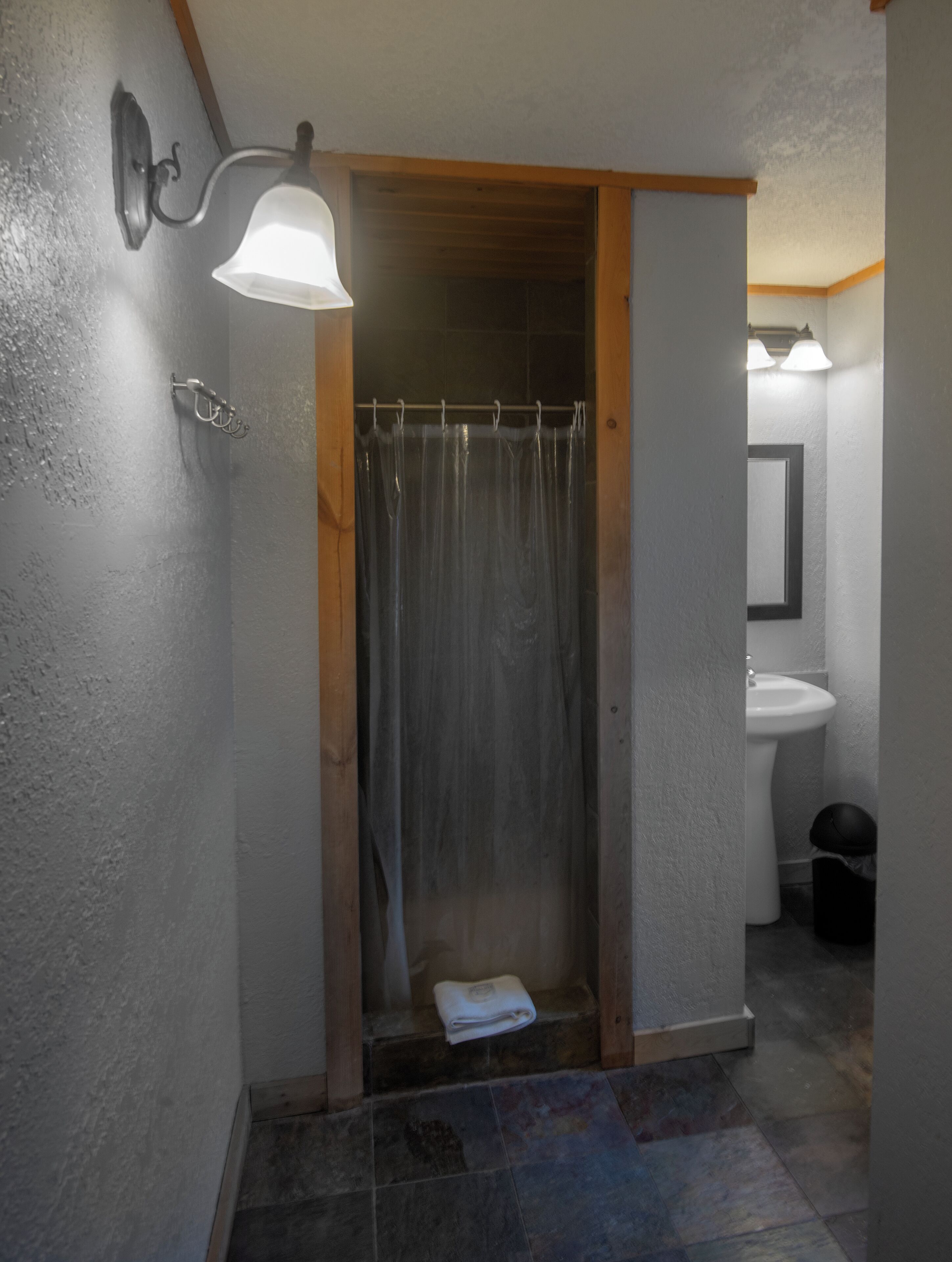 A bathroom with a shower, a sink, and a towel on the floor.