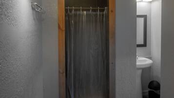 Un baño con ducha, lavabo y una toalla en el suelo.