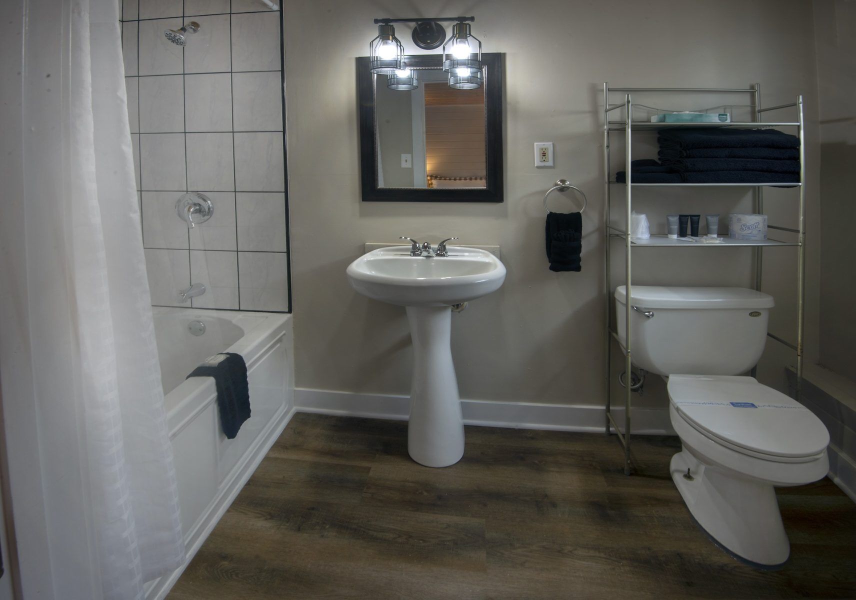 A bathroom with a bathtub, a sink, a toilet, and a mirror.