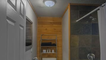 A bathroom with a white sink, toilet, and bathtub. There is a wooden panel wall and a shower area with a glass door.