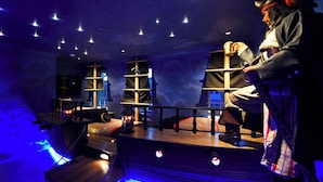 Ein Zimmer mit Holzschiff-Design, darunter ein Schiffsrad und Regale.