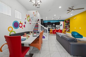 A modern living room with a dining area, a staircase, and a kitchen.
