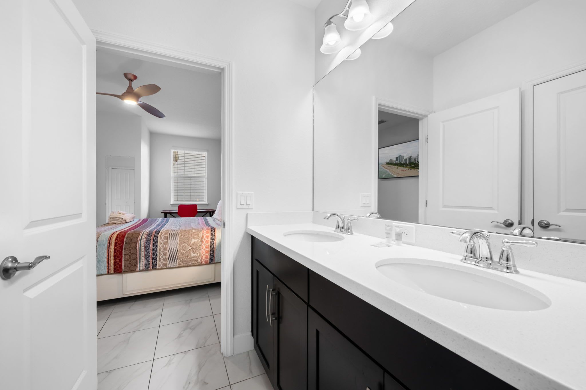 Un bagno moderno con due lavabi, un grande specchio e una ventola a soffitto.