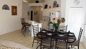 A dining area with a table set for four, surrounded by chairs. A kitchen is visible in the background. - Value | Private Pool | Game Room | Disney 1616 (Clermont)