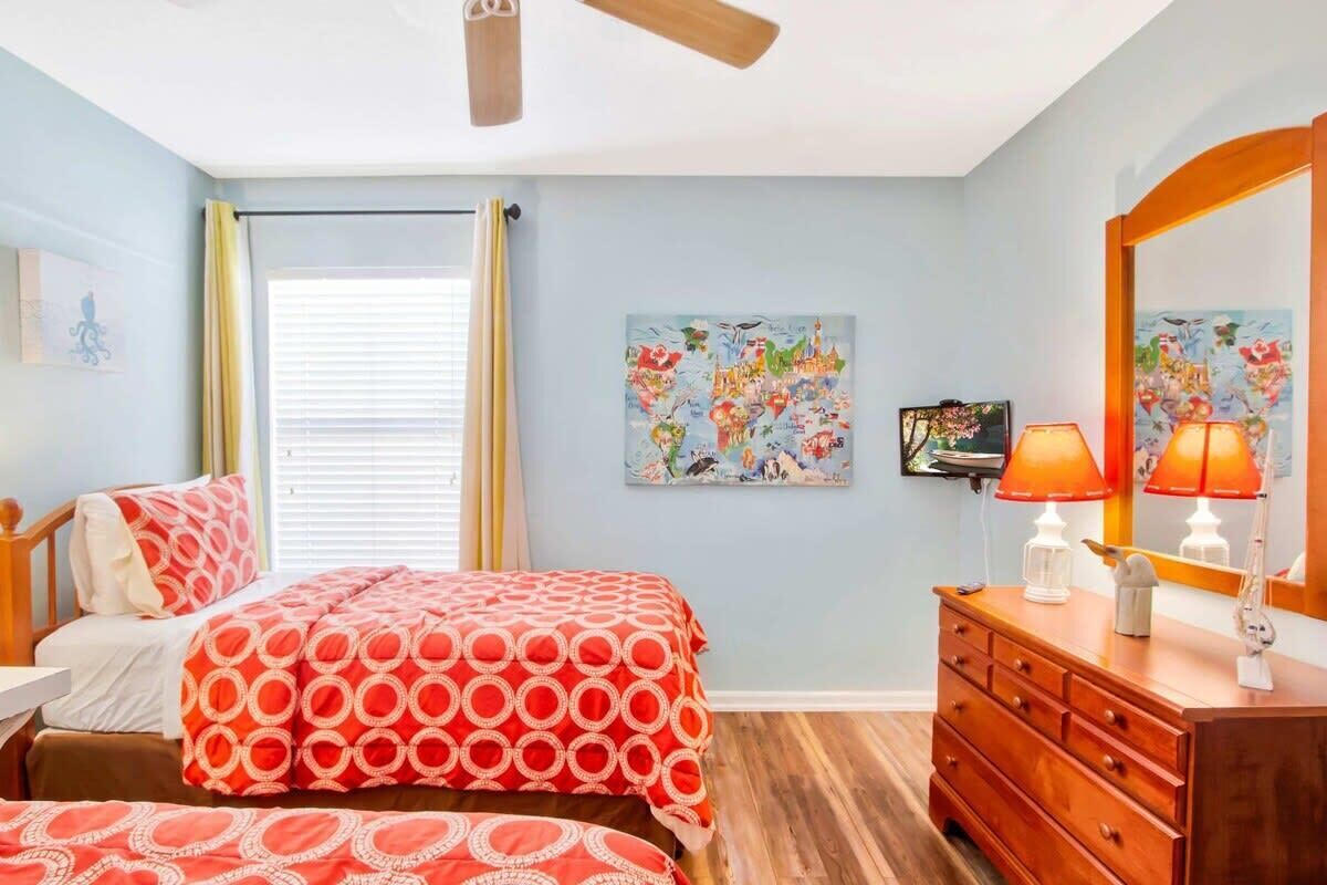 Un dormitorio con cama, cómoda, ventilador de techo y ventana con cortinas.