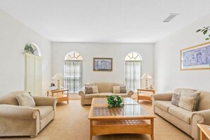 Relax in this stylish living room with two sofas, a coffee table, and side tables with lamps, surrounded by framed artwork.