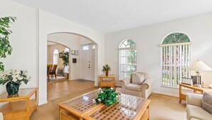 A spacious living room with a large coffee table, a sofa, and a dining area in the background. - Conservation View | Pool & Spa | 7 Miles Disney 203 (Davenport)
