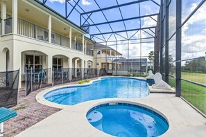 A swimming pool with a glass enclosure, a covered patio, and a view of the surrounding landscape.