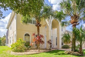 Stunning two-story building with arched windows and a central entrance, set amidst a beautifully manicured lawn and palm trees.