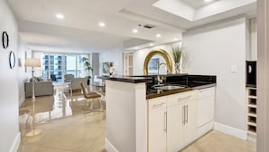A modern kitchen with a central island, white cabinetry, and a black countertop. - Sauna | Hot Tub | Skyline & Bay Views | StayCozy (Miami)