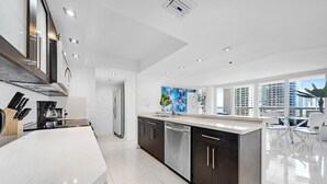 A modern kitchen with a large island, stainless steel appliances, and a view of the city through large windows.
