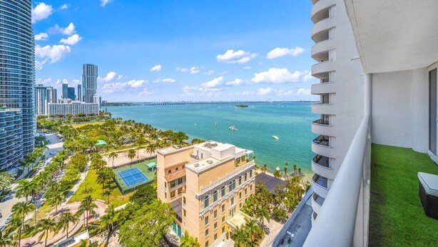 A high-rise building with a view of a marina and city skyline.