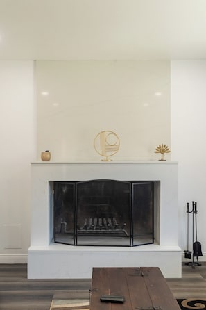 A modern living room with a fireplace, a wooden table, and a bench.
