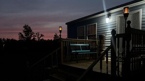 A wooden deck with a bench and a staircase leading to a house.