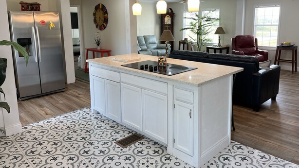 A modern kitchen with a central island, stainless steel refrigerator, and pendant lighting.