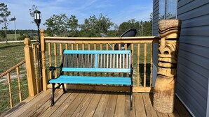 A wooden deck with a blue bench, a stone pillar, and a satellite dish.