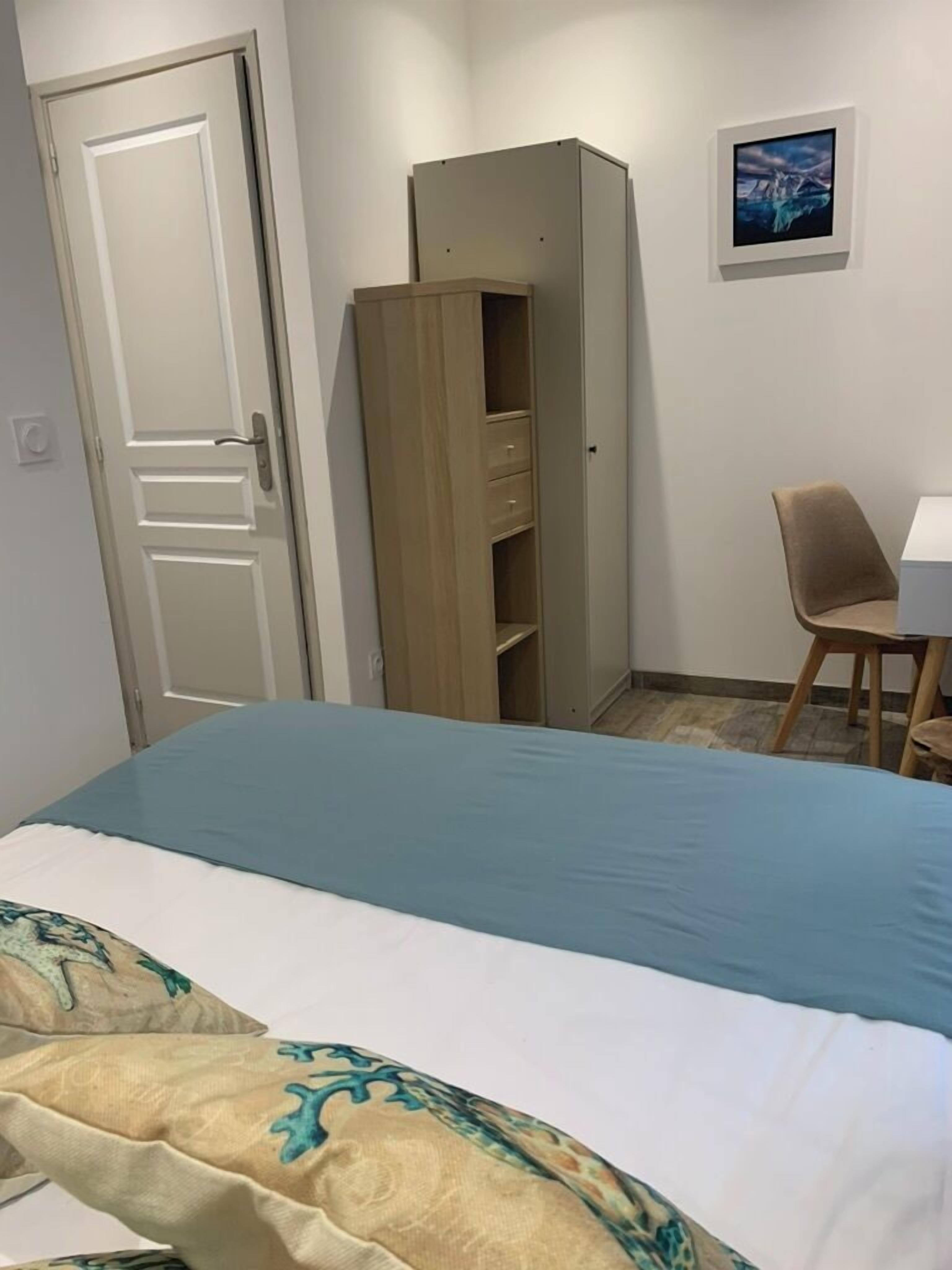 A bedroom with a bed, a wardrobe, a desk, and a chair.