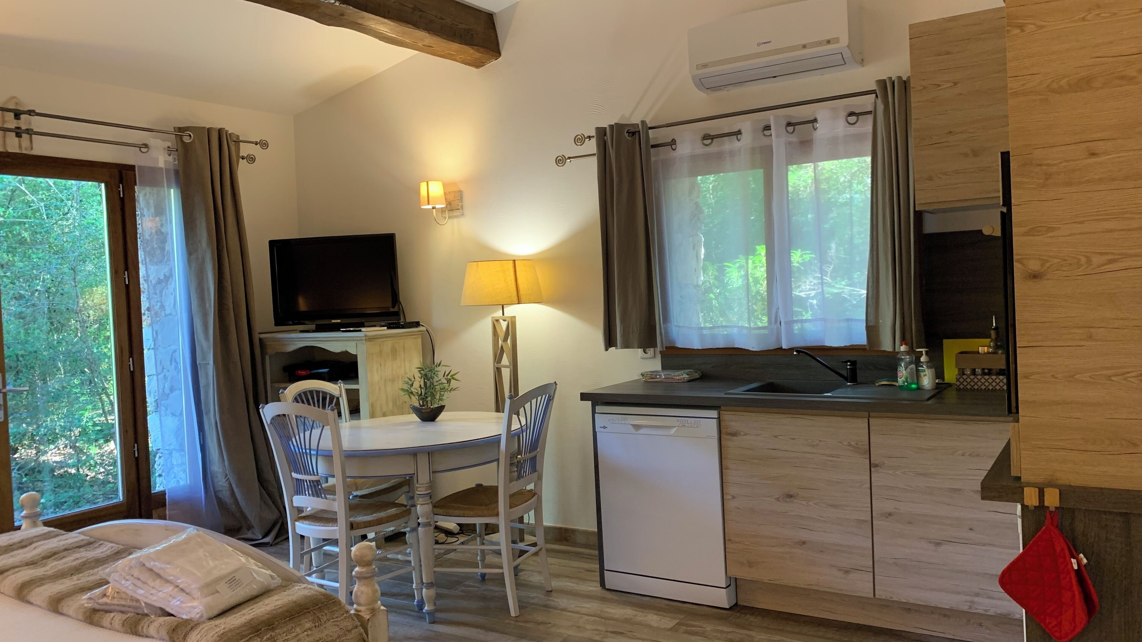 A compact kitchen with a dining area, a television, and a window with curtains.