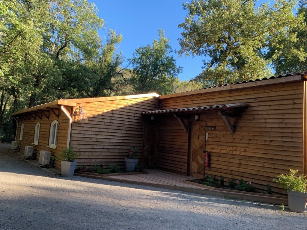 A wooden cabin with a porch, a fire extinguisher, and potted plants.