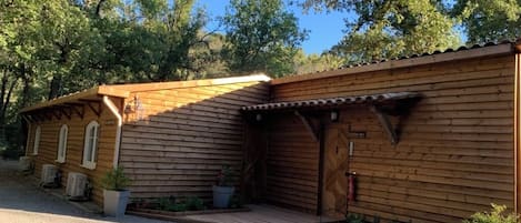 A wooden cabin with a porch, a fire extinguisher, and potted plants.