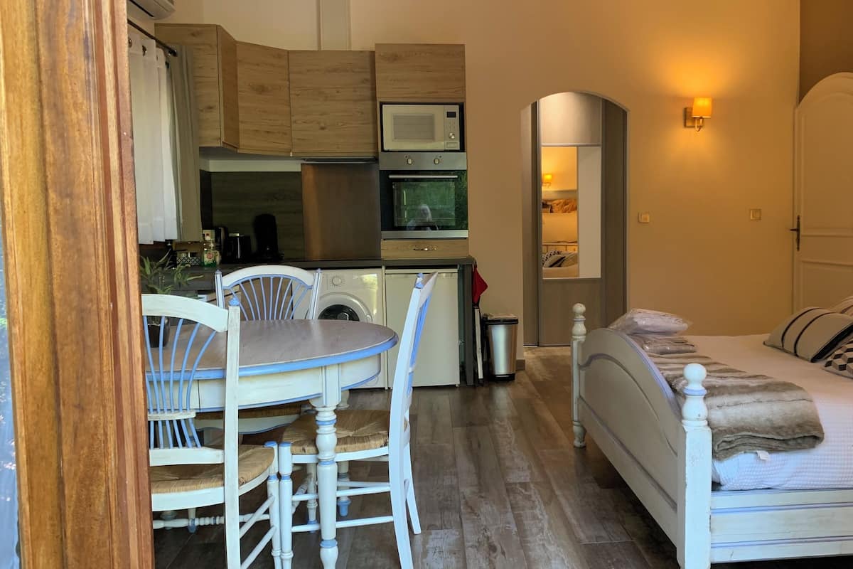 Una habitación funcional con mesa de comedor, sillas, cama y kitchenette.