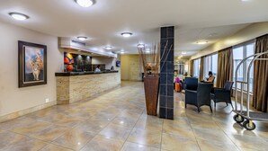 A hotel lobby with a reception desk, seating area, and large windows. - African Sky Hotels - Ermelo Inn (Ermelo)
